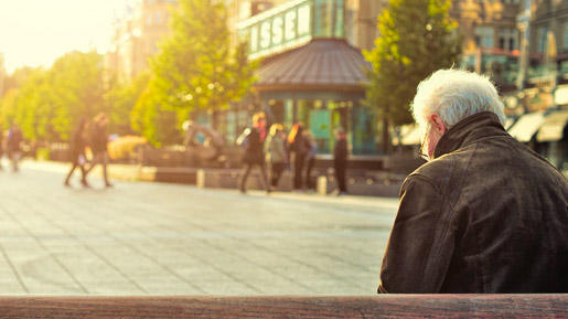 Ältere Person auf Bank sitzend.